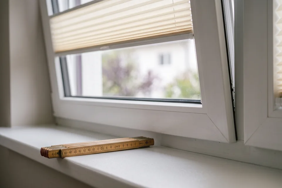 Zollstock am Fensterfluegel eines Plissees